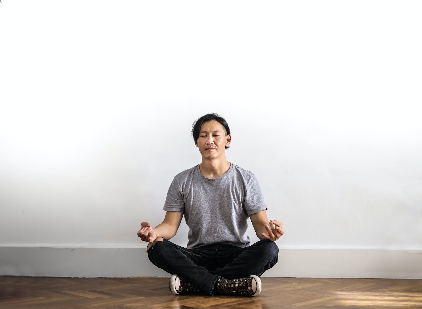 photo of man in gray t shirt and black jeans on sitting on wooden floor meditating
Photo by Andrea Piacquadio on Pexels.com