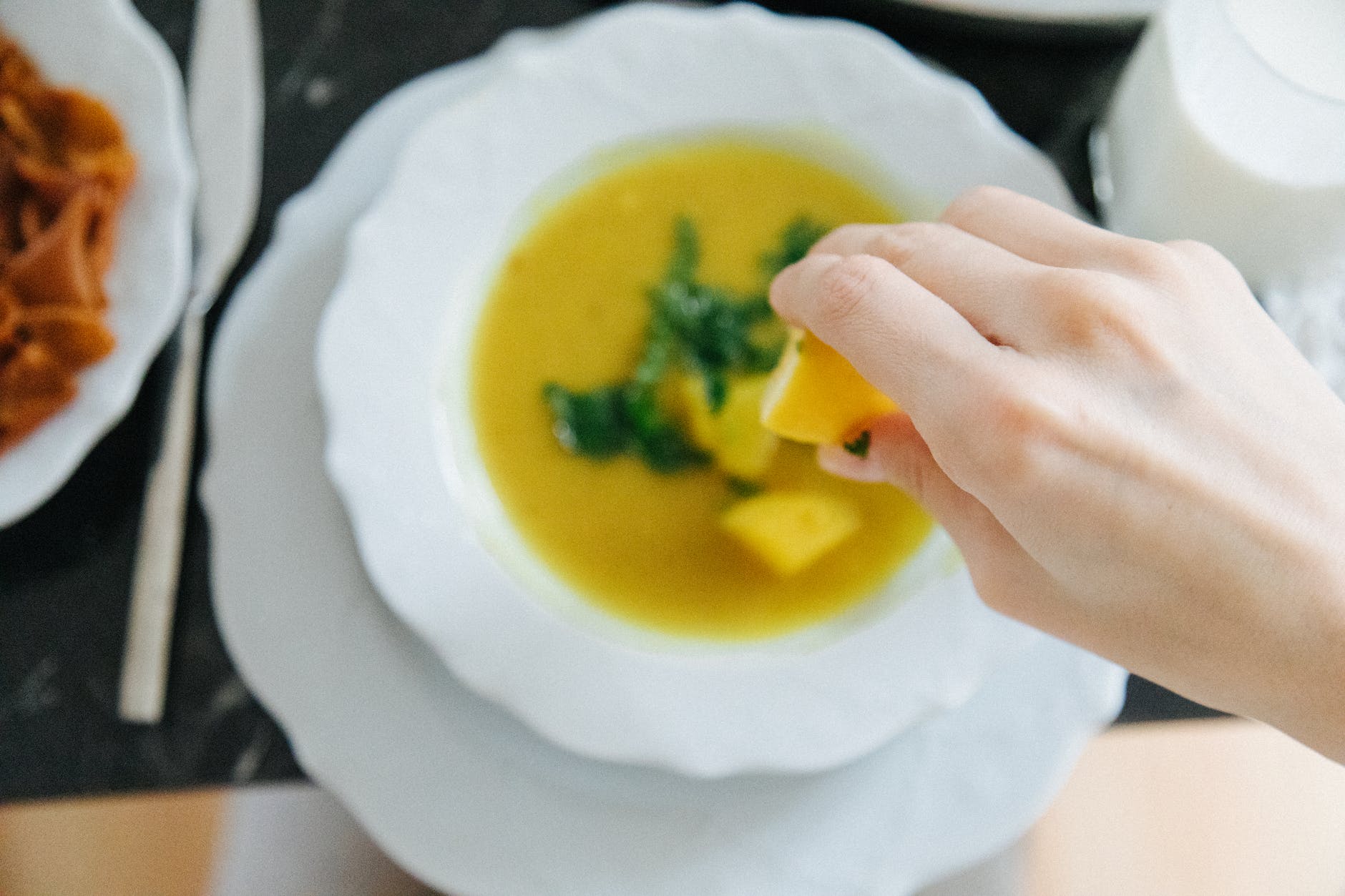 a person squeezing a lemon on lentil soup